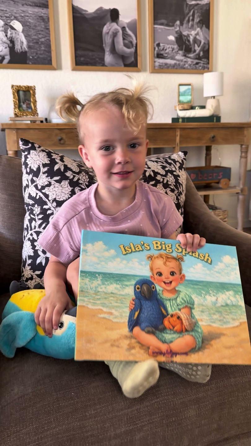 Isla holding her personalized PlotJoys book — that’s her illustrated as the hero on the cover